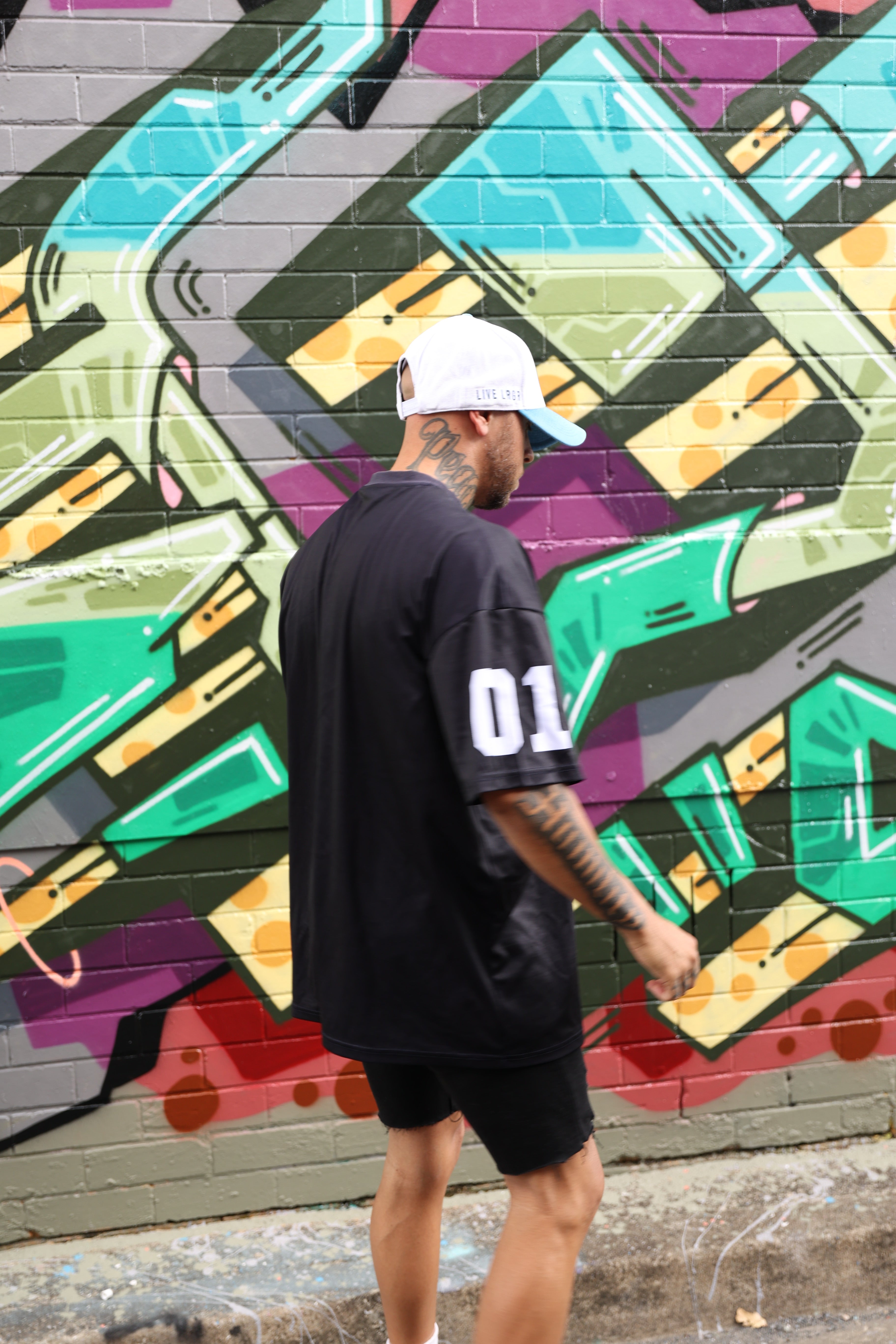 A people standing on a colorful street mural wearing a LRGR t-shirt
