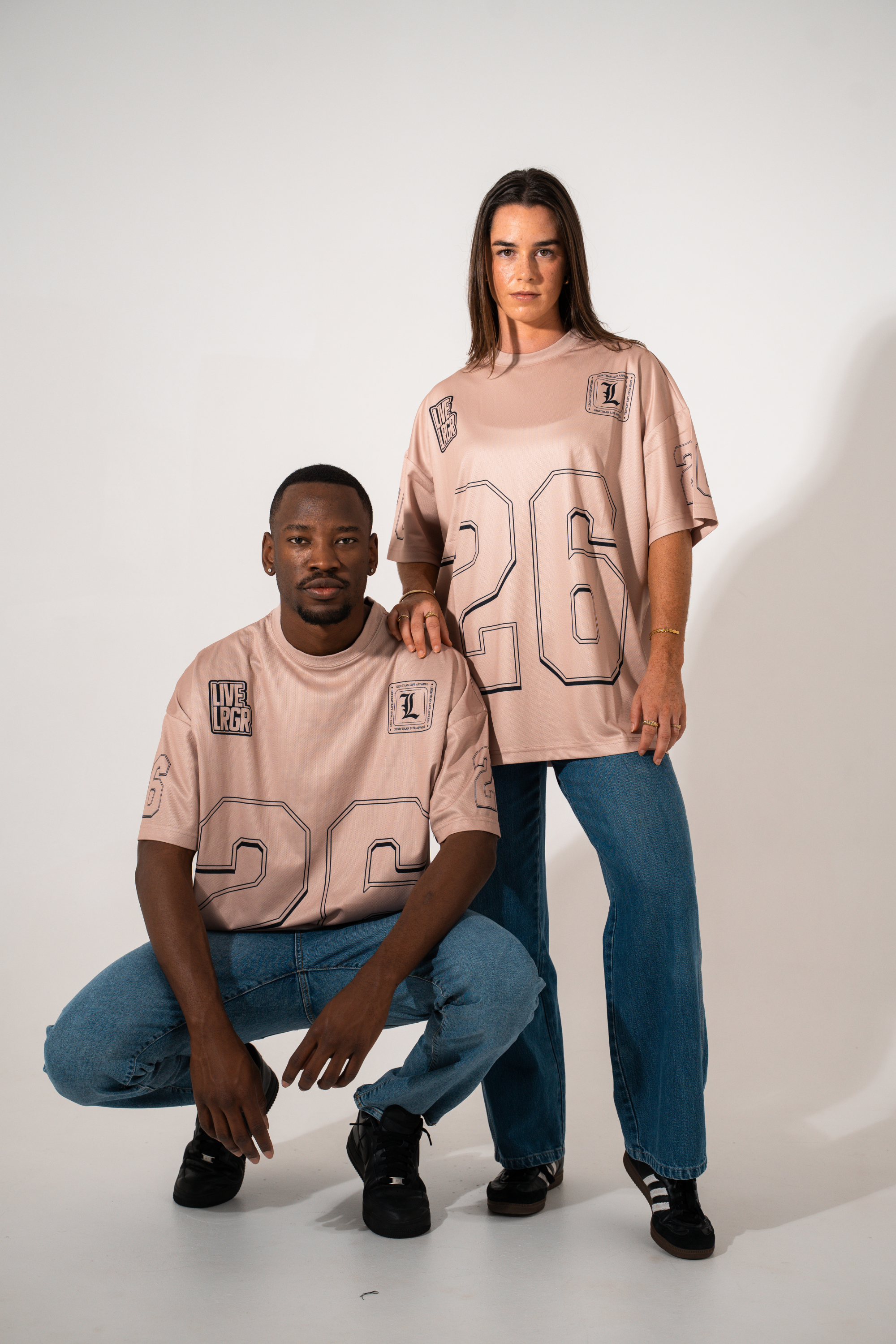 Two people wearing matching pink t-shirts with large numbers on a white background
