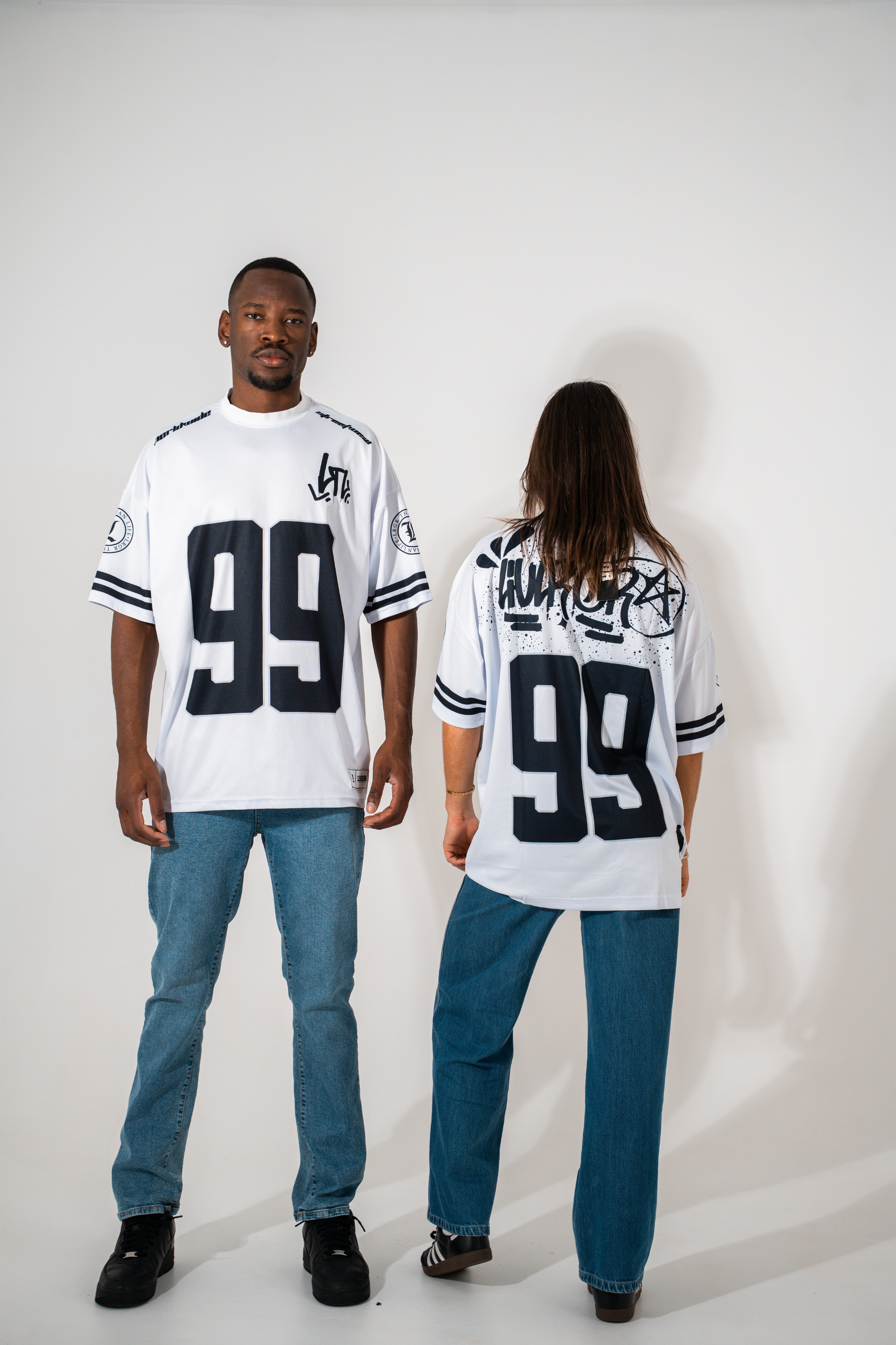 Two people wearing white jerseys with the number 99, one facing forward and the other facing backward, on a plain background.