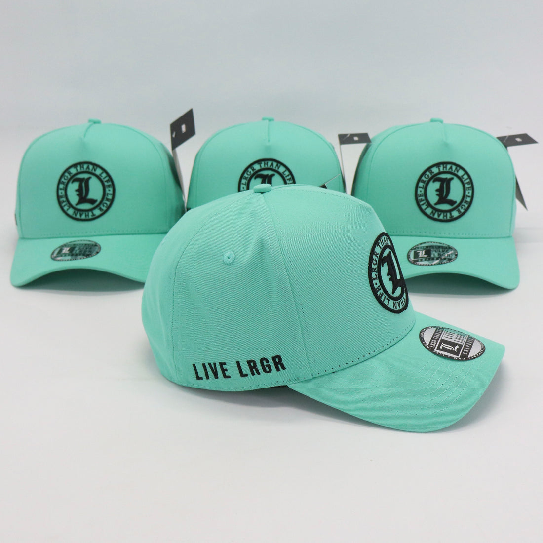 Four mint green caps with black logos on a light gray background