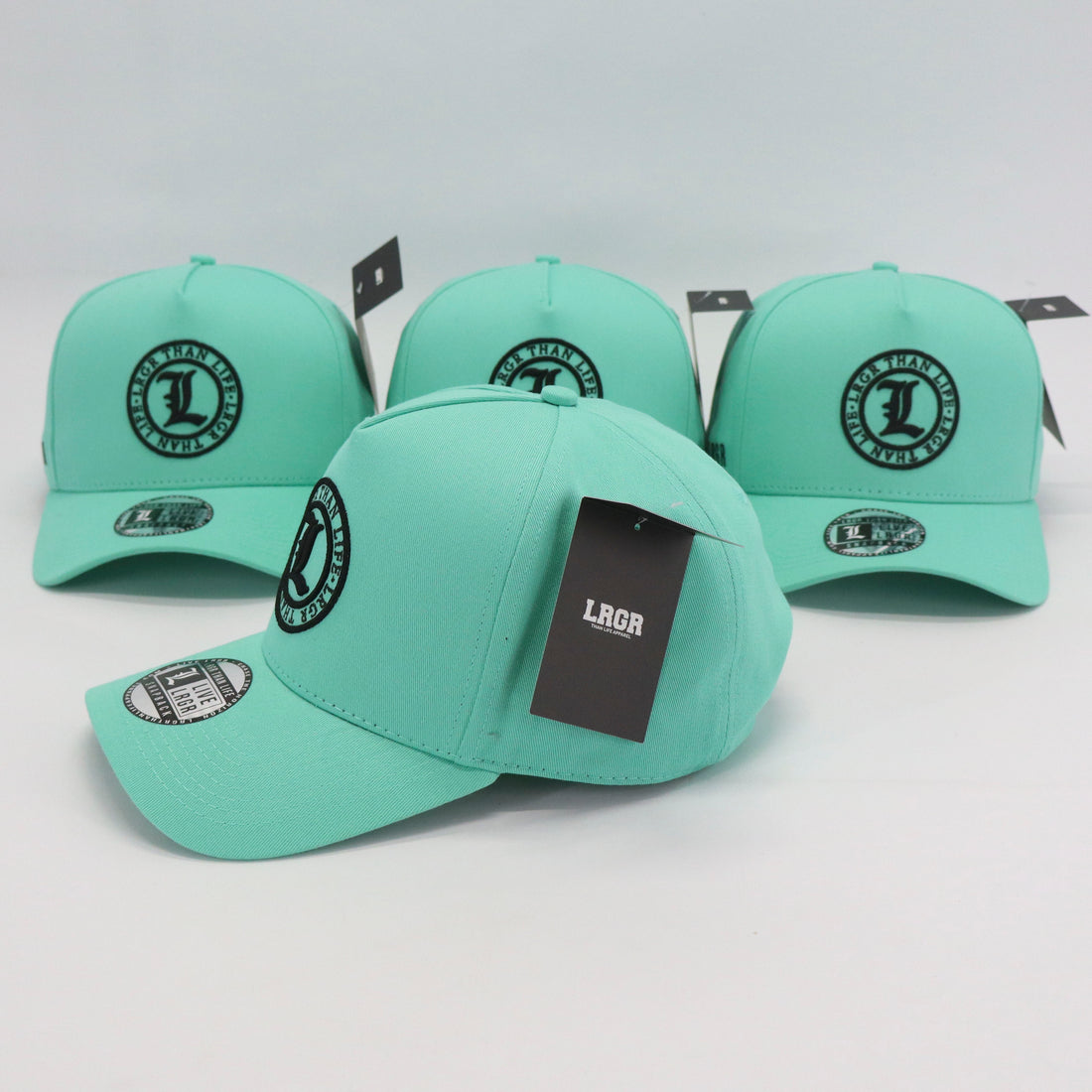 Three mint green caps with black logos on a light gray background