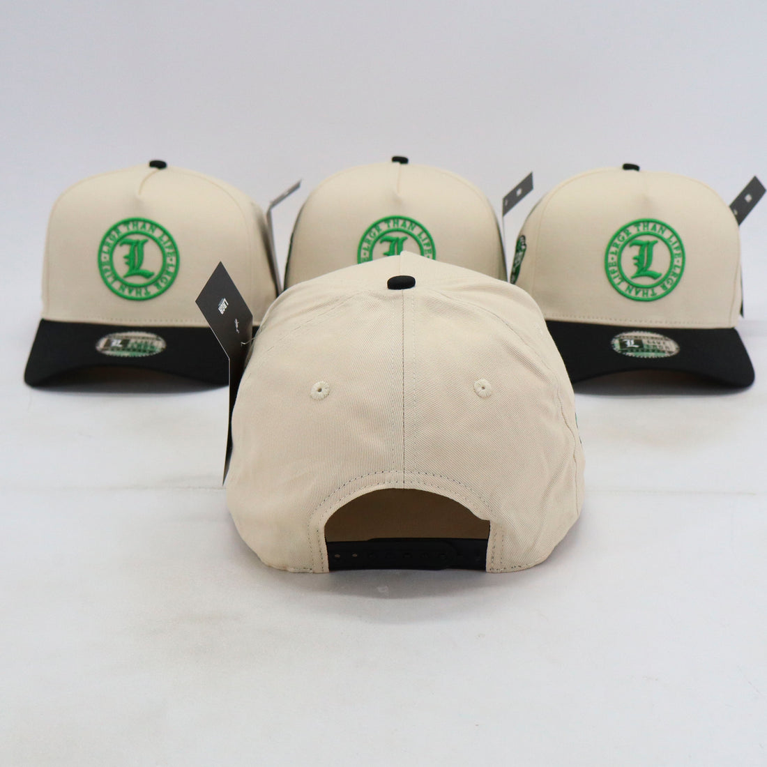 Four beige baseball caps with green logos on a white background