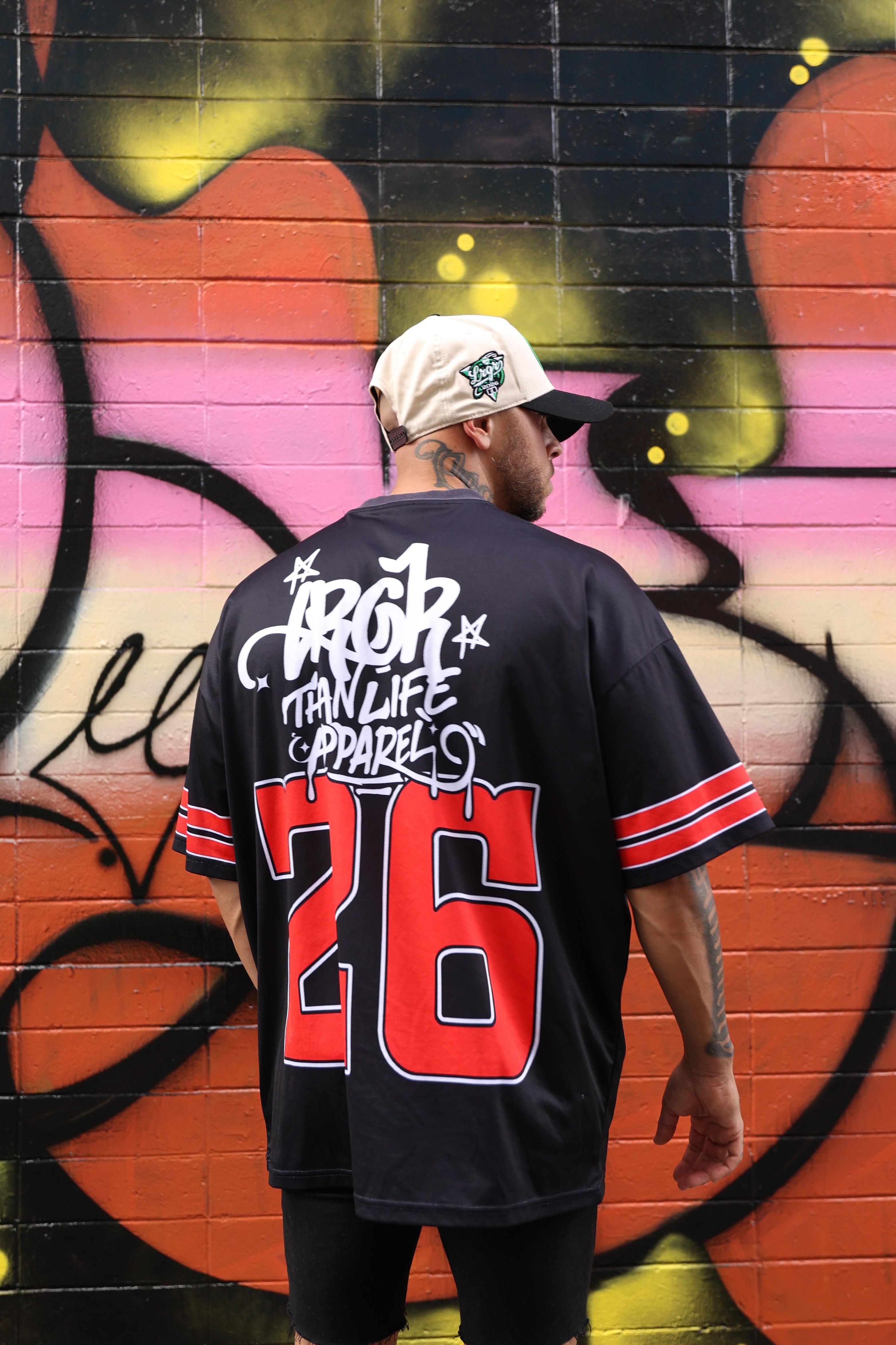 Person wearing a LRGR black hoodie with red and white text, standing in front of a colorful graffiti wall.