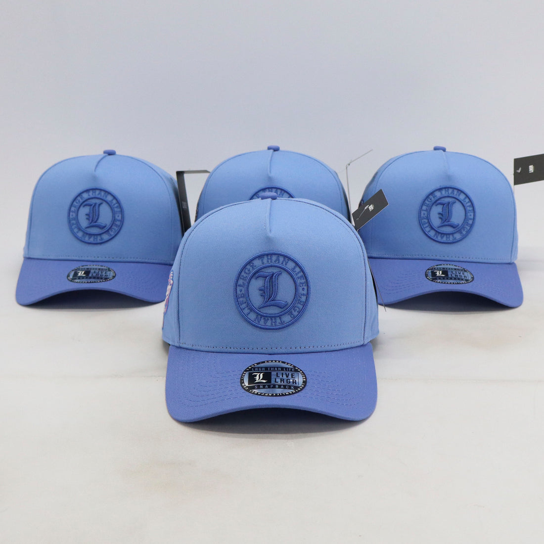 Four blue baseball caps with a logo on a white background