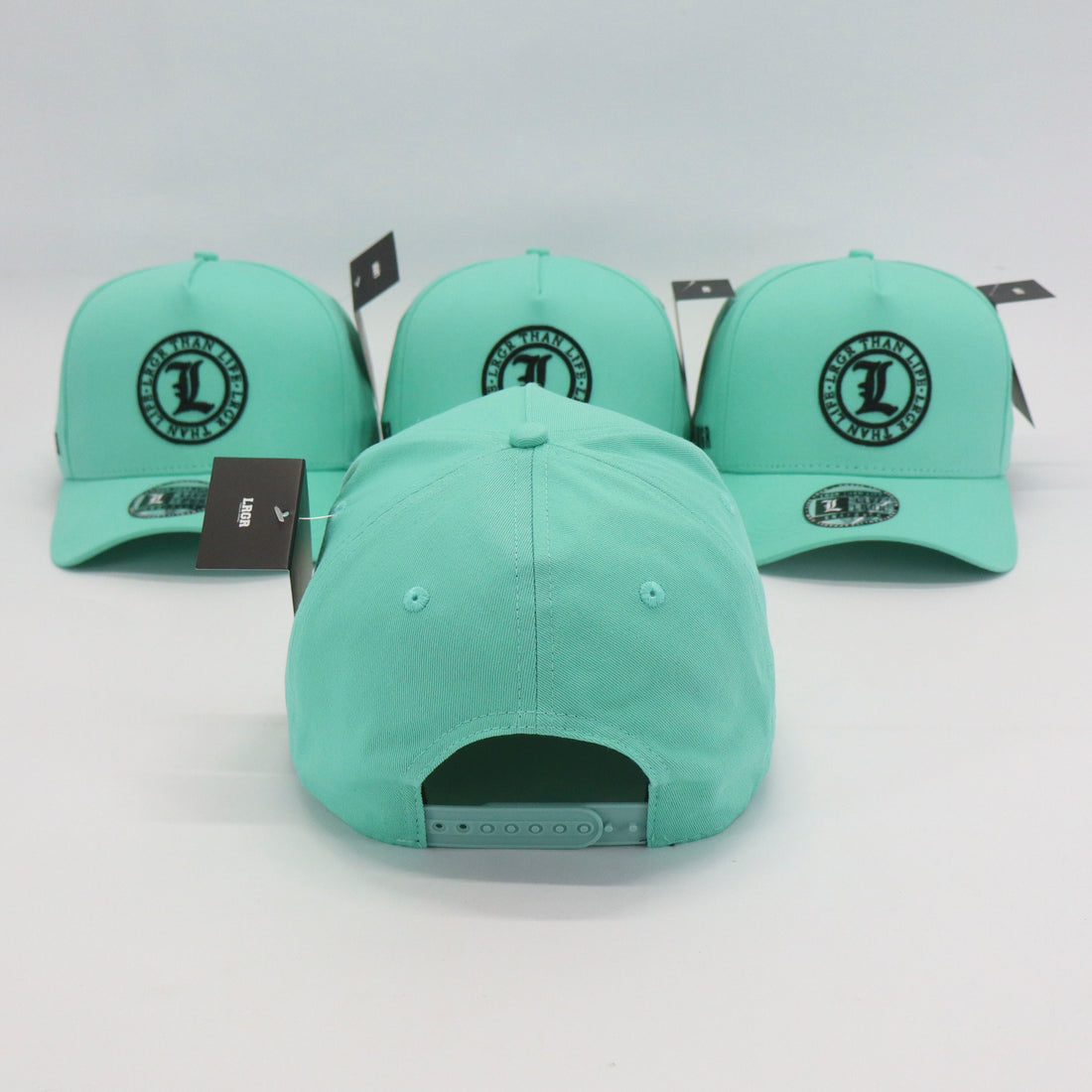 Three mint green baseball caps with a logo on a white background