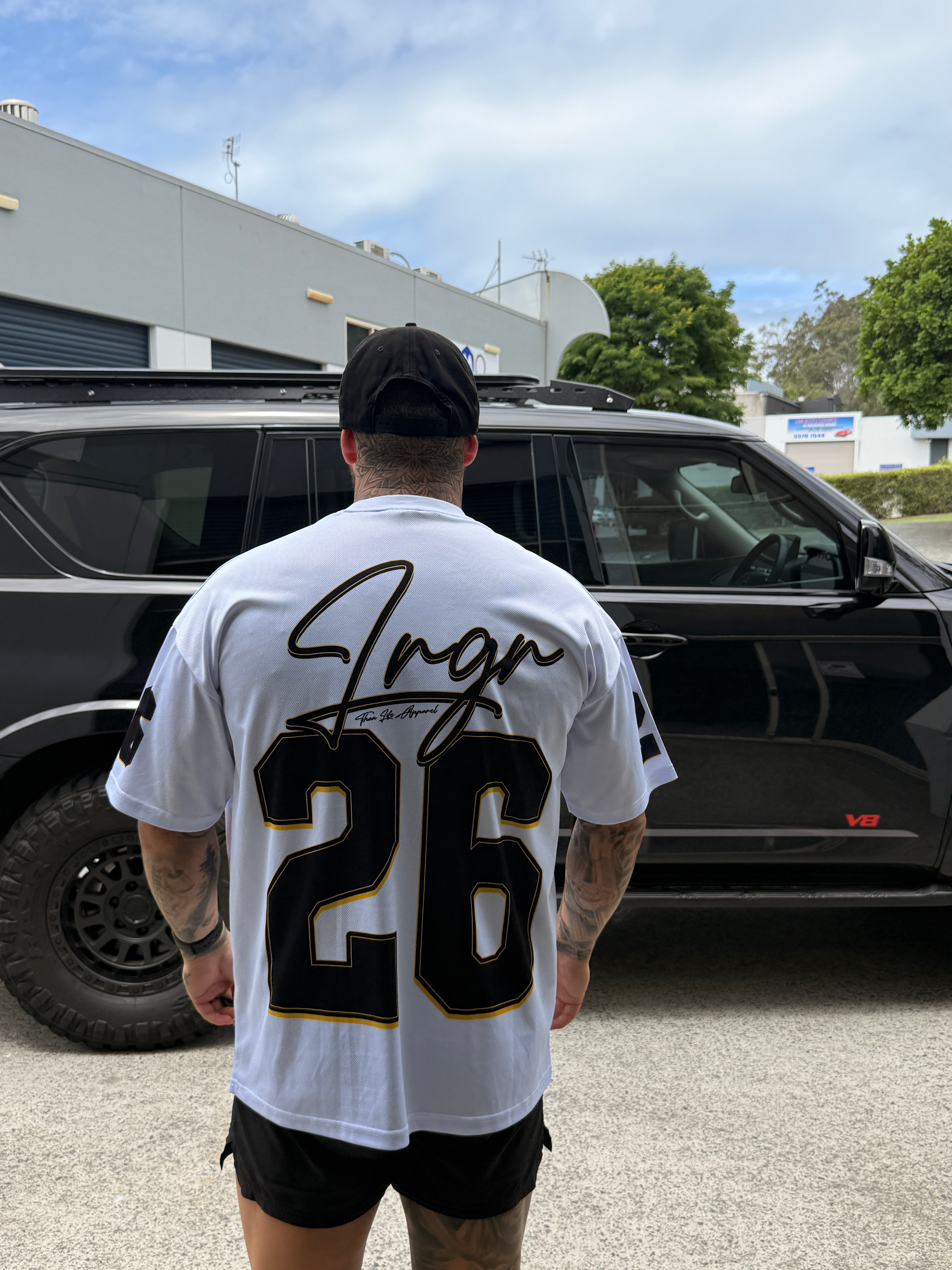 Person holding a LRGR sports jersey with a number in front of a black car.