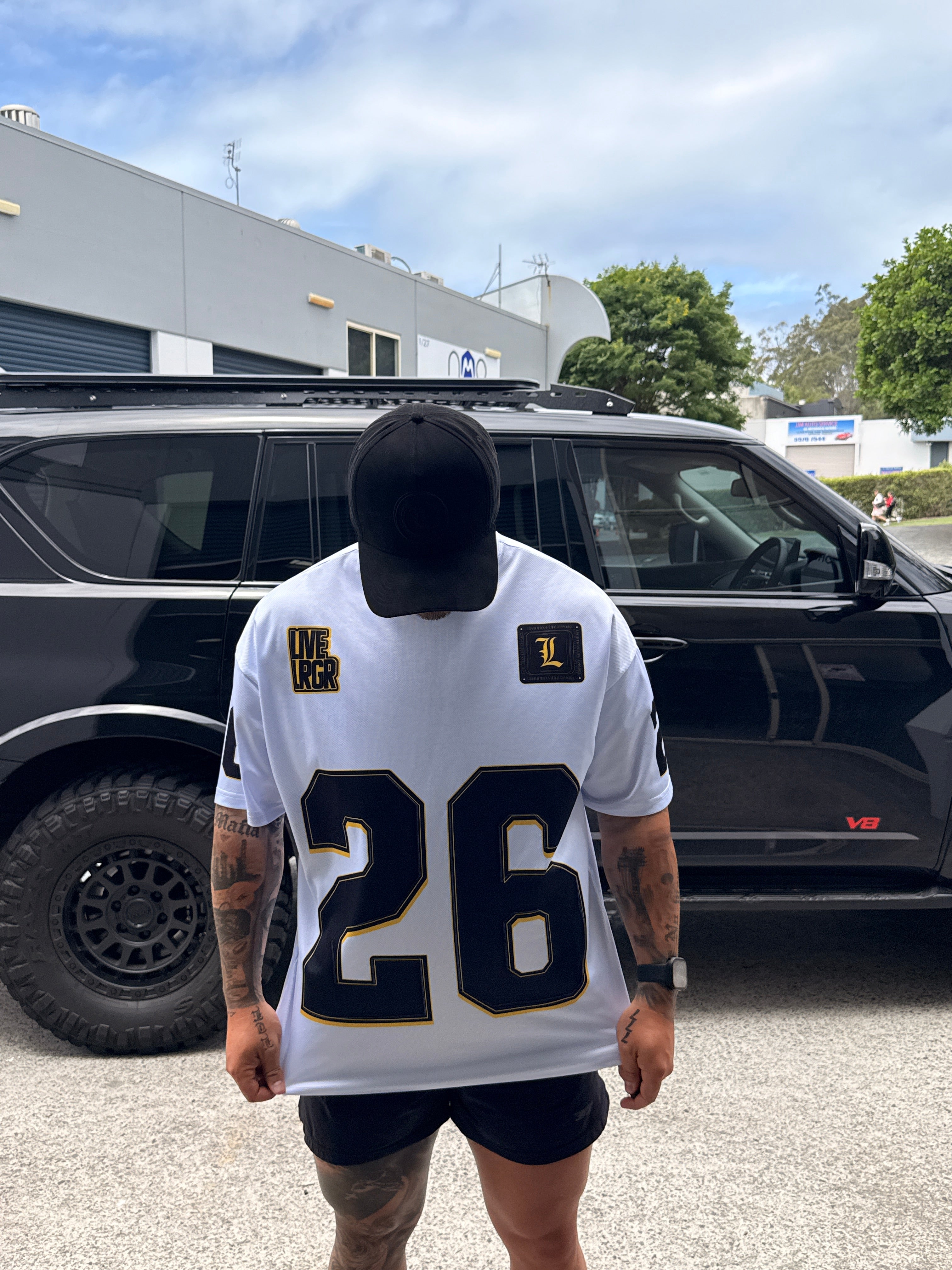 Person holding a LRGR sports jersey with a number in front of a black car.