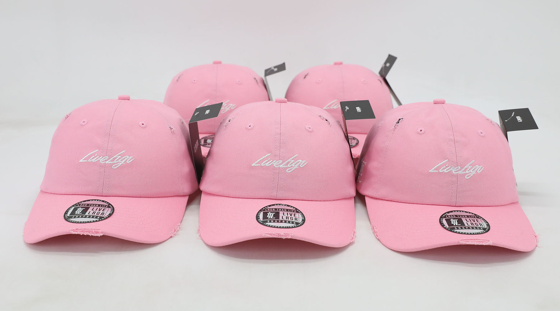 Three pink dad hats with the text 'LUVIG' on them placed against a white background.