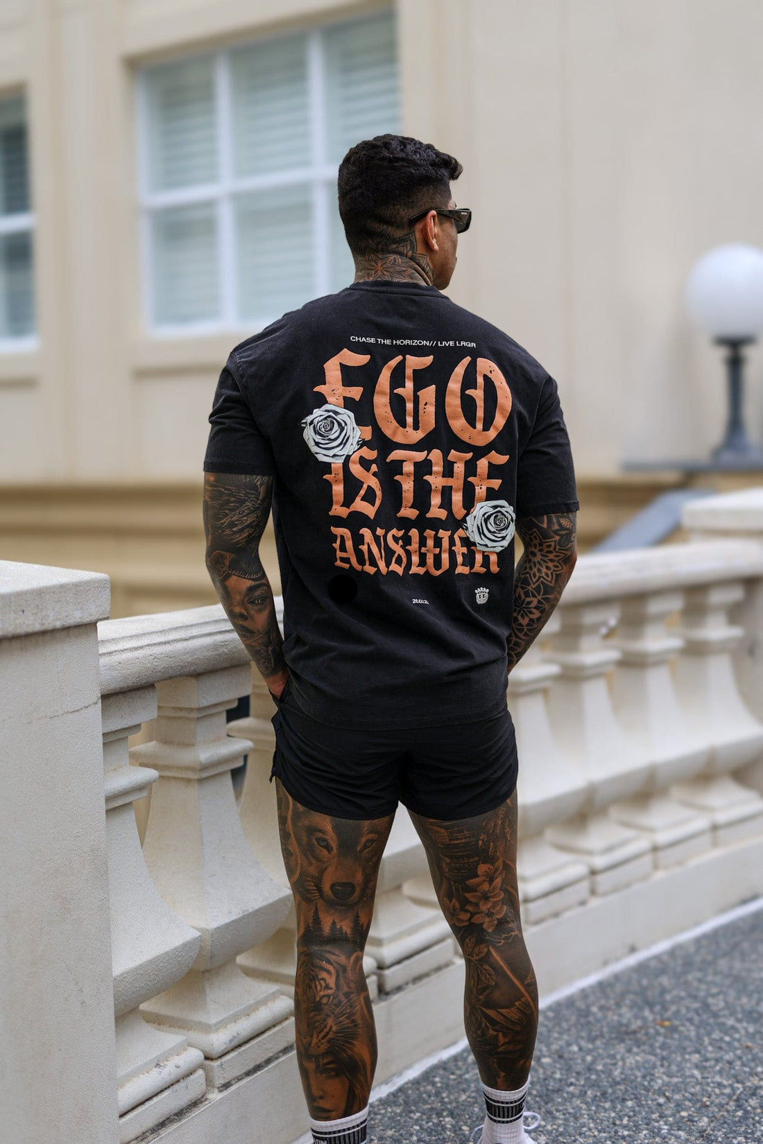 Man wearing a black t-shirt with 'EGO IS THE ANSWER' text, standing outdoors.