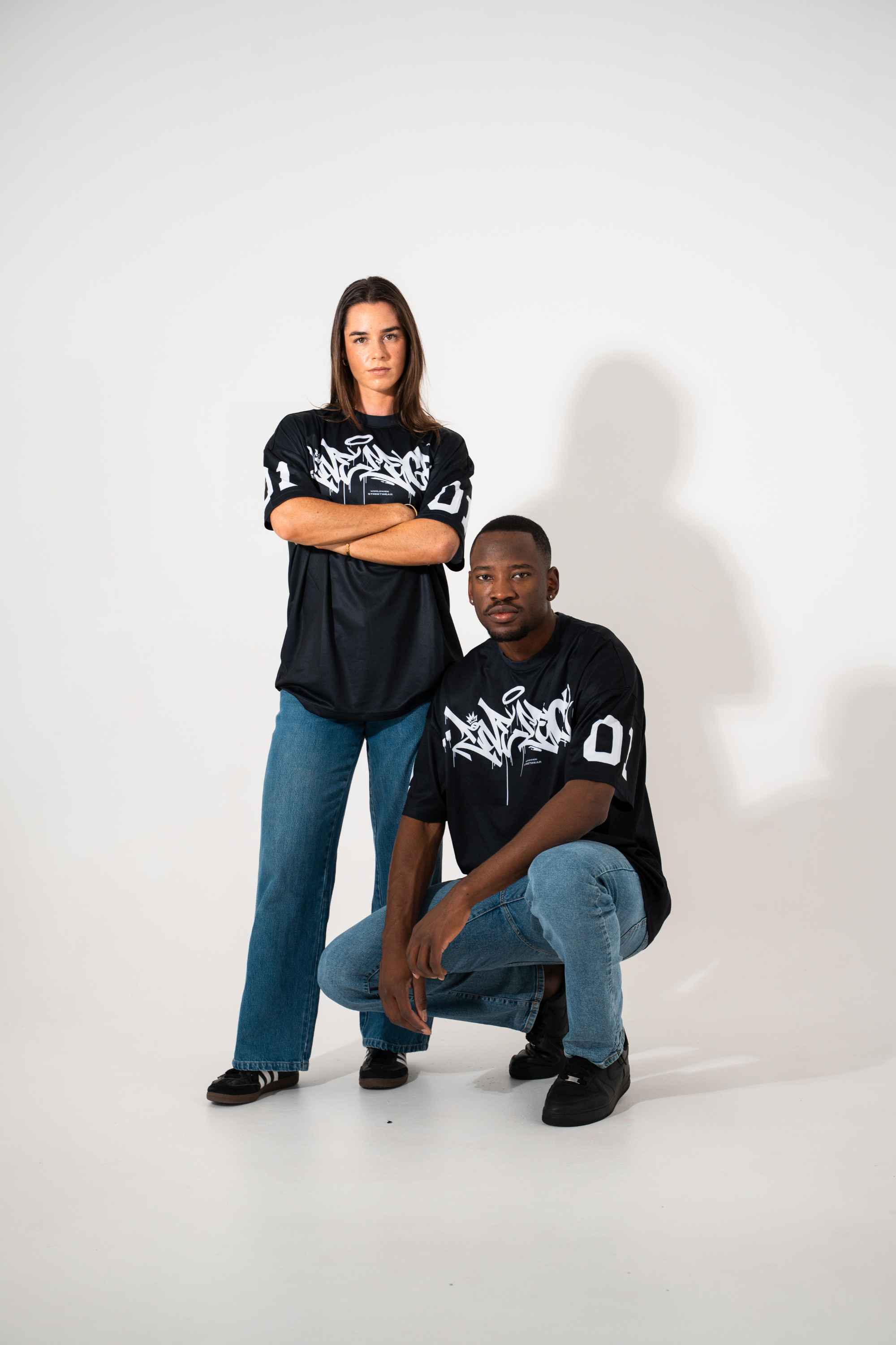 Two people wearing black t-shirts with white graphics on a white background