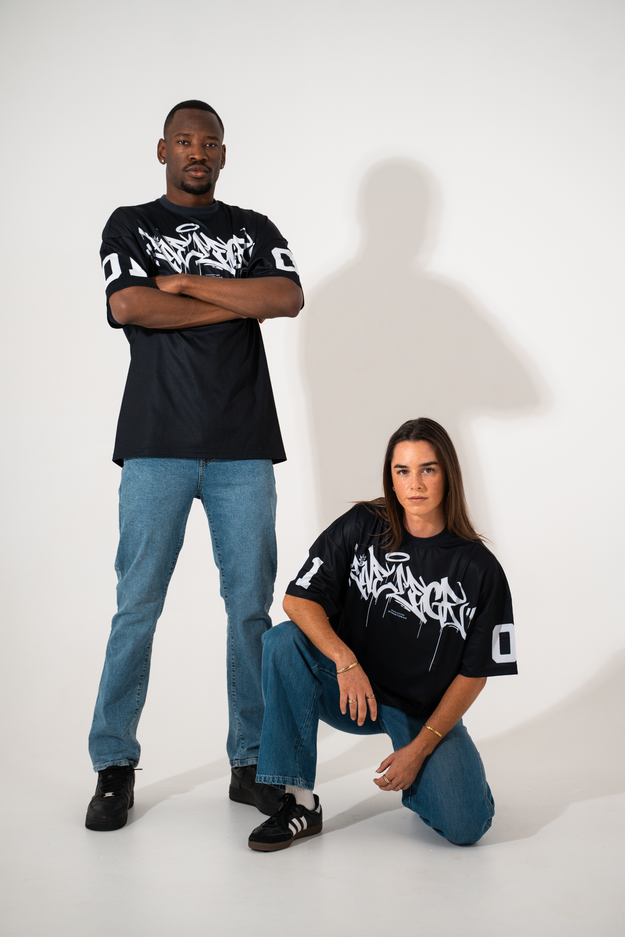 Two people wearing black t-shirts with white graphics on a white background