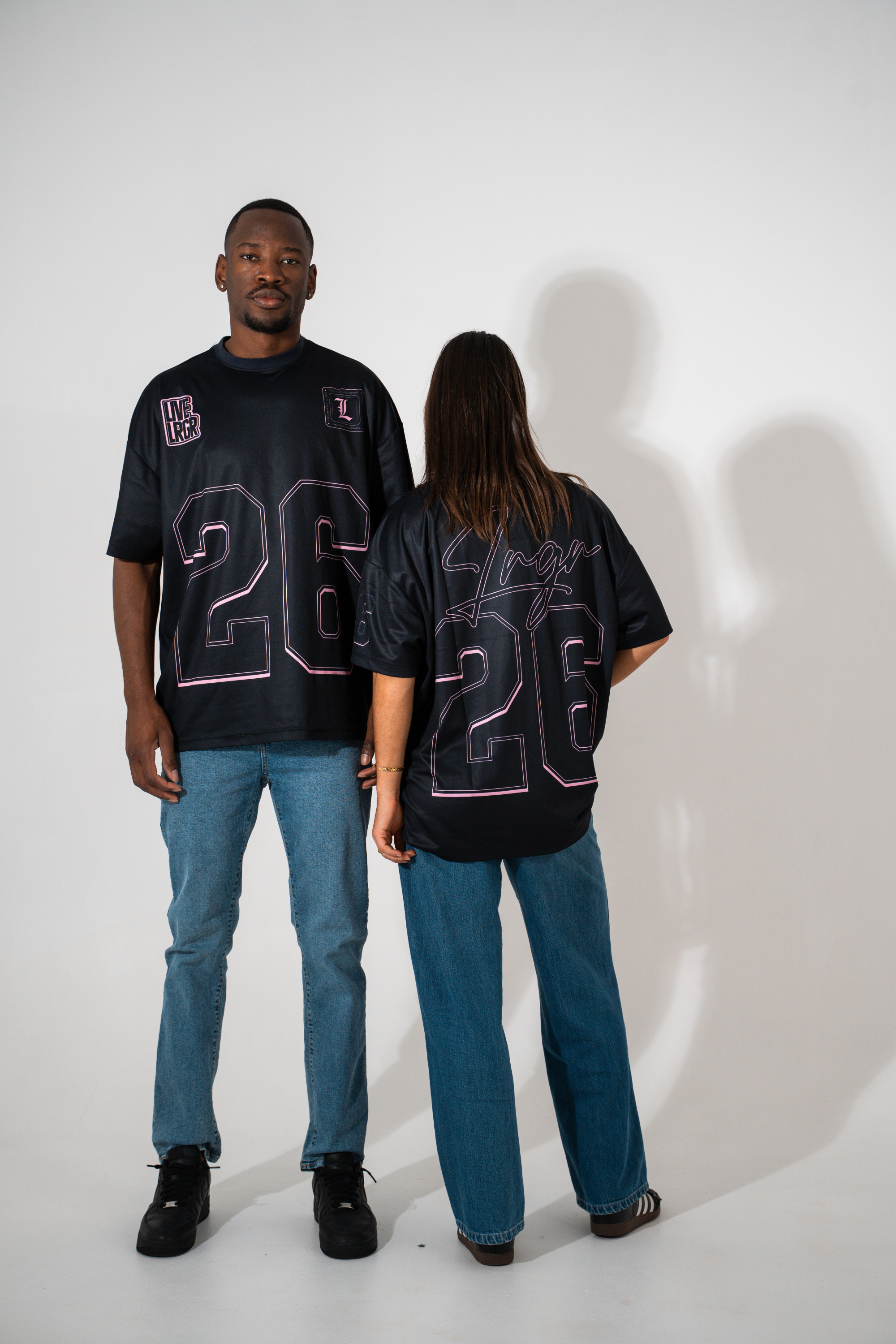 Two people wearing matching black t-shirts with the number 26 on a white background