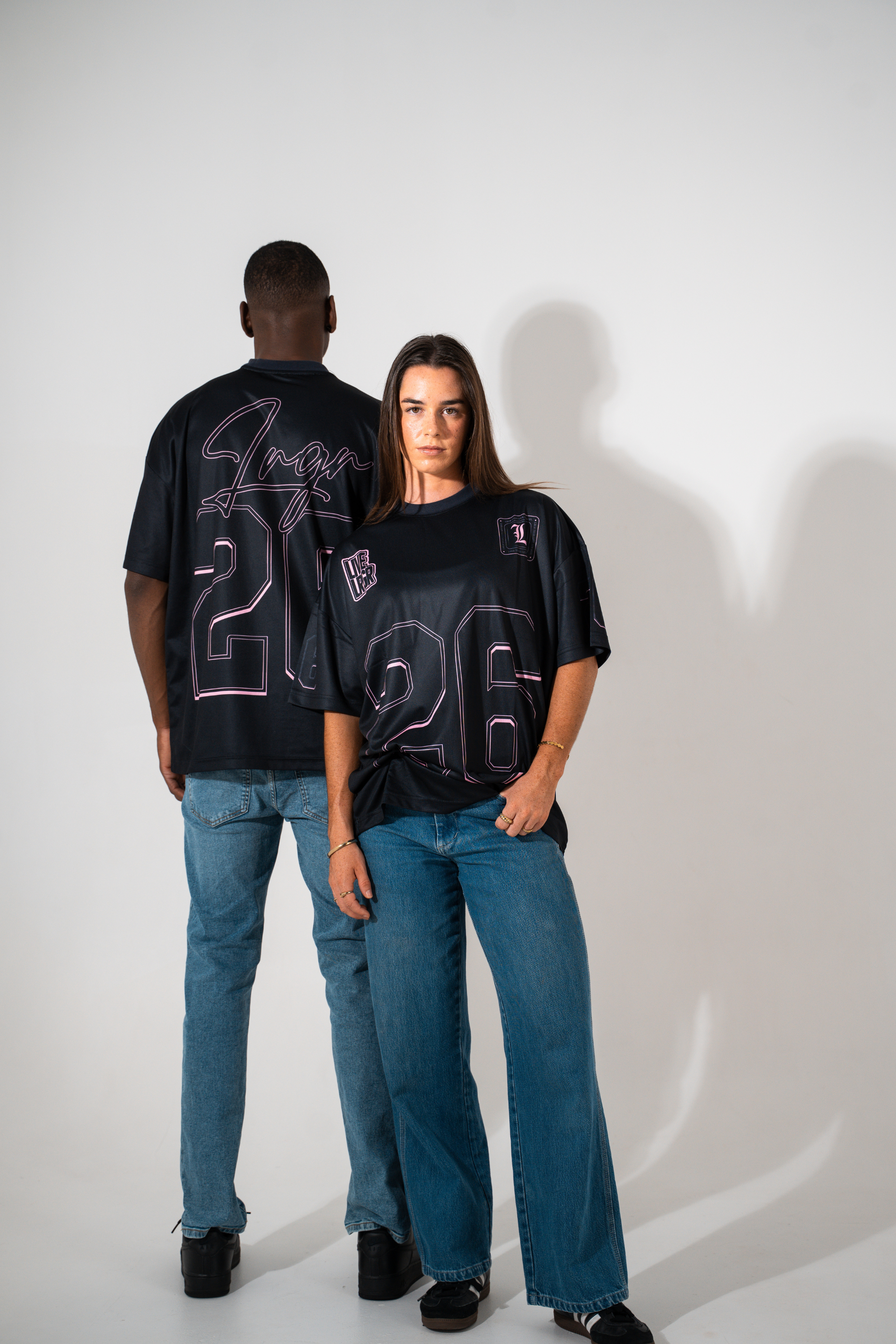 Two people wearing black t-shirts with numbers on a white background
